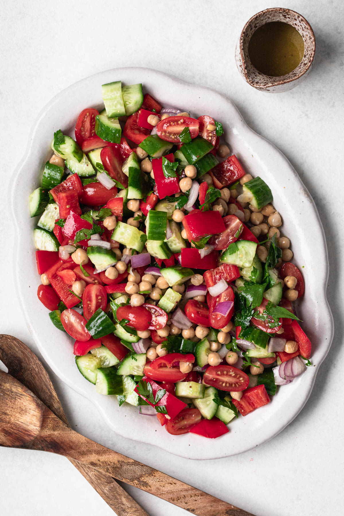 Chopped salad of cucumber, cherry tomatoes, red onion, parsley and chickpeas on an oval platter