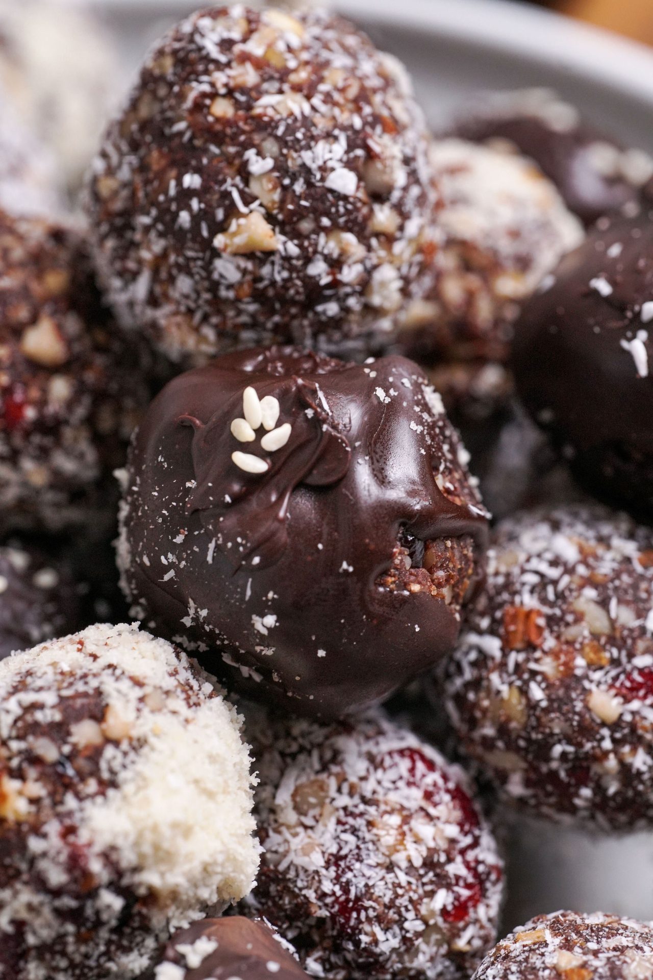 Close up shot of cranberry date cacao bliss ball truffles with melted dark chocolate.