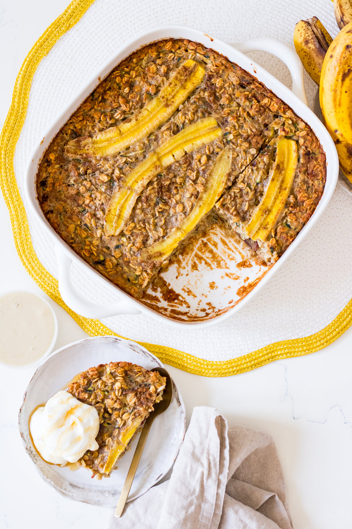 Square white ceramic dish with baked oats with banana and grated zucchini