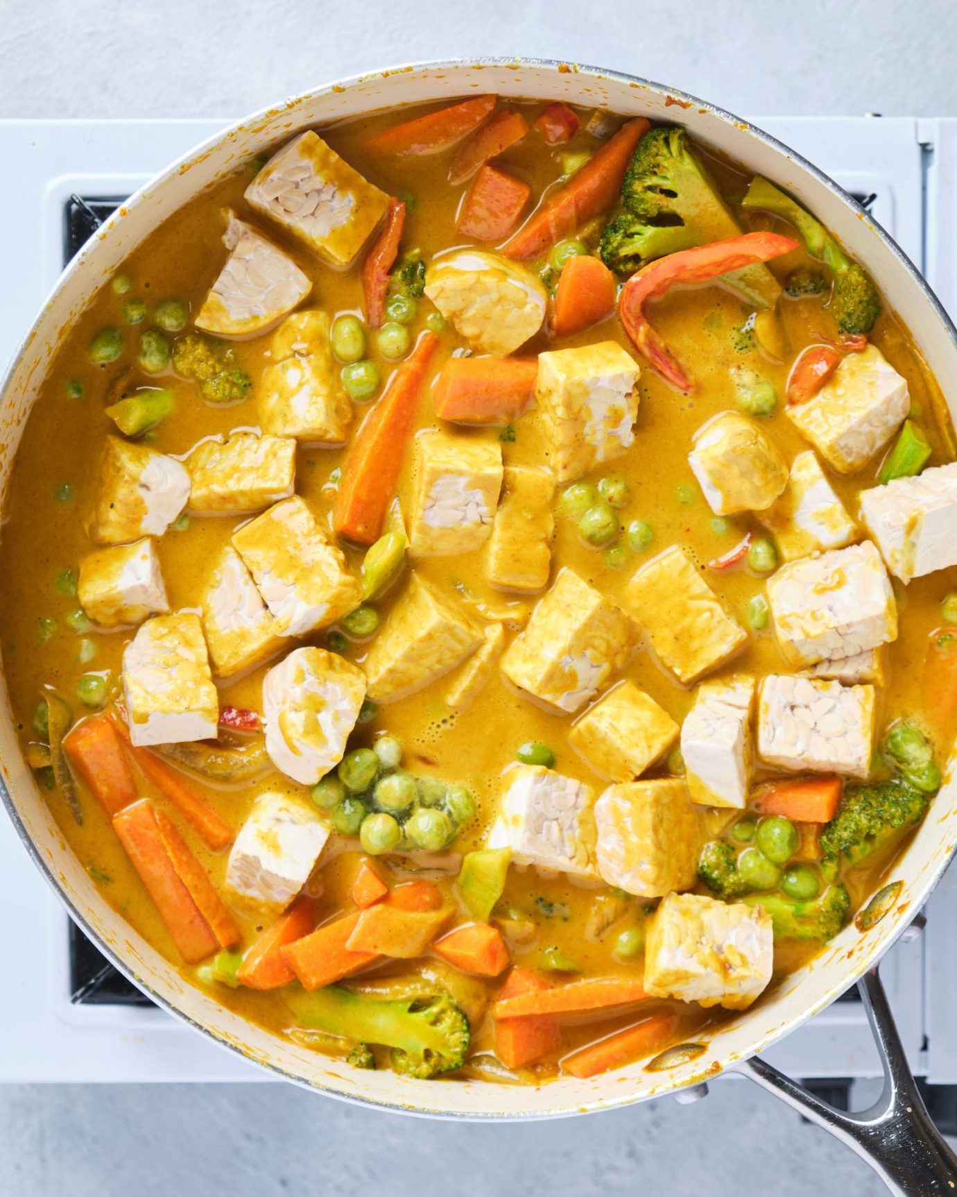 Tempeh yellow curry cooking in a large frypan