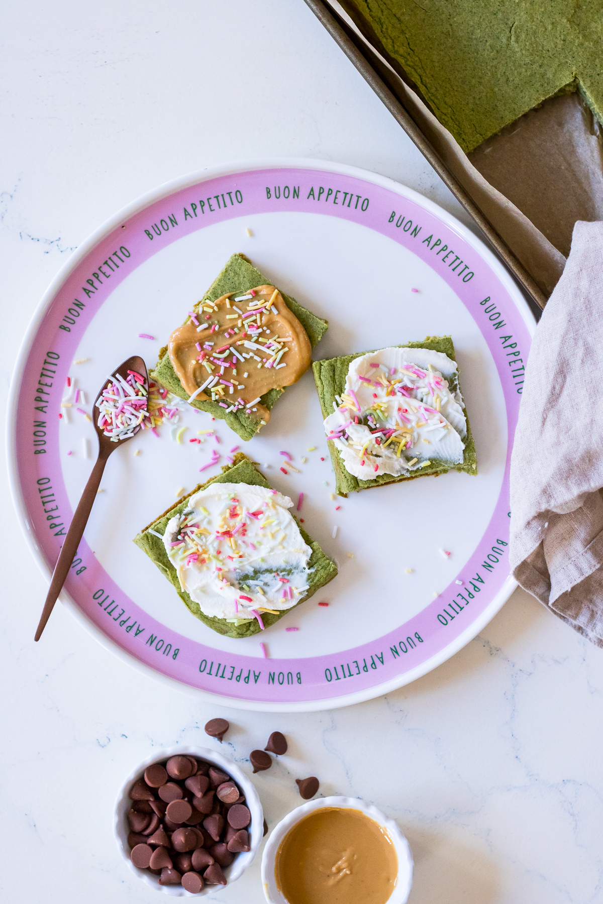 Image of green pancakes cut into square shape with peanut butter or cream cheese and sprinkles