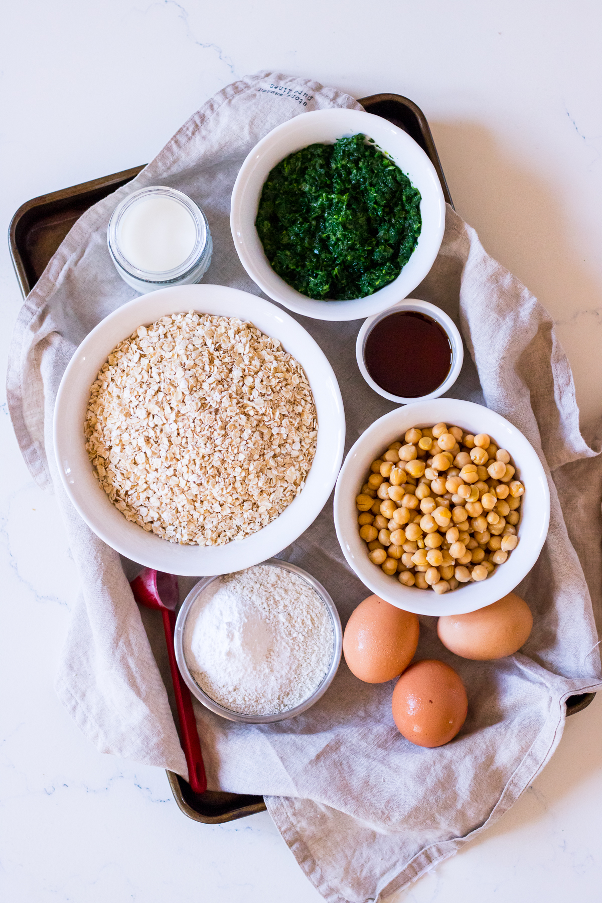 Ingredients to make healthy pancakes arranged into bowls including spinach, oats, eggs and chickpeas
