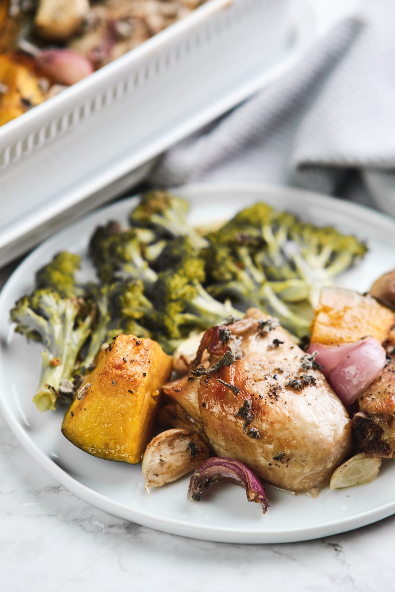 Image of a dinner plate with roast chicken, pumpkin, broccoli and herbs