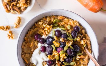 Carrot cake oatmeal topped with Greek yoghurt, blueberries and walnuts in a small bowl