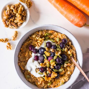 Carrot cake oatmeal topped with Greek yoghurt, blueberries and walnuts in a small bowl