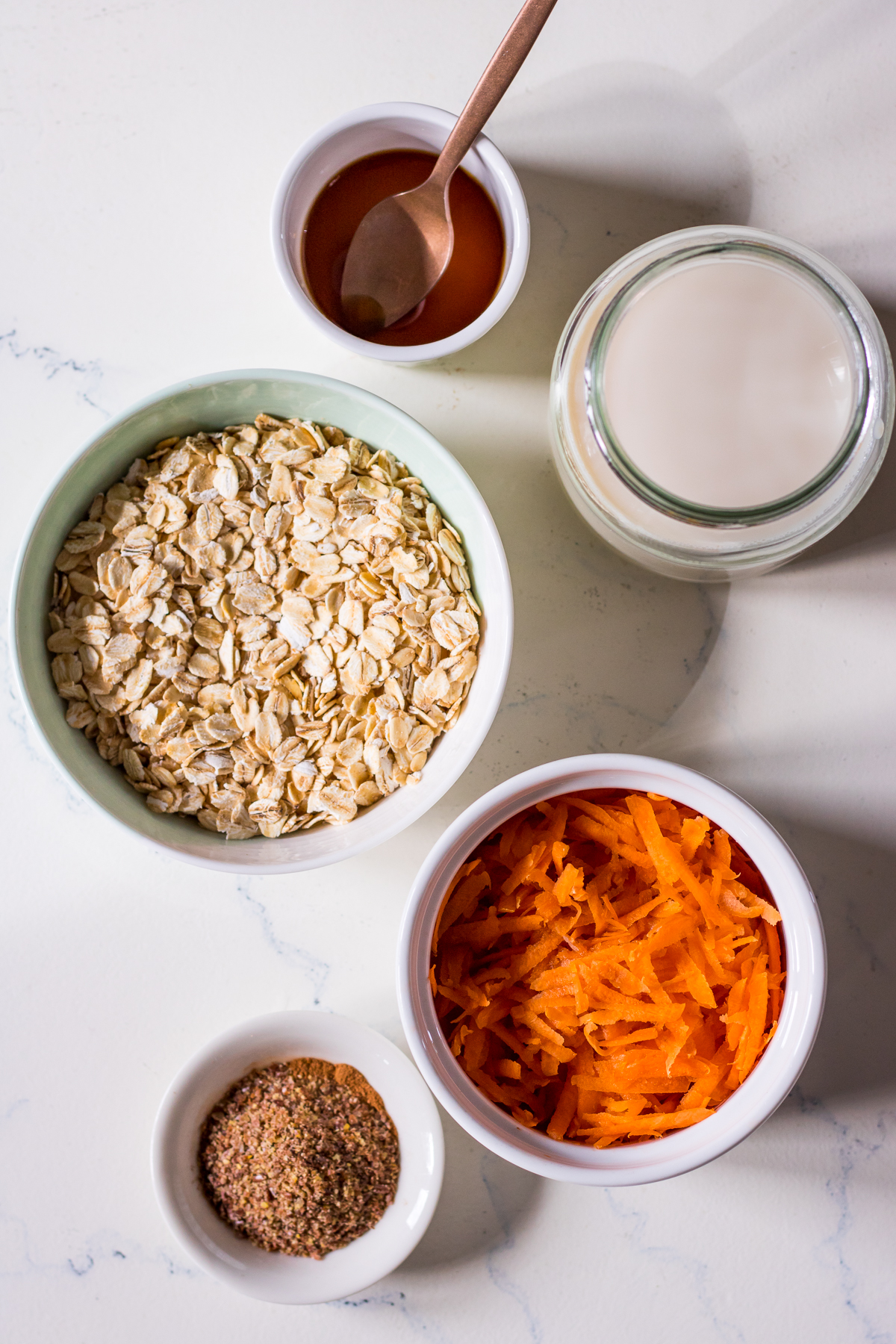 Porridge ingredients arranged into small dishes, top down view, oats and carrots and spices