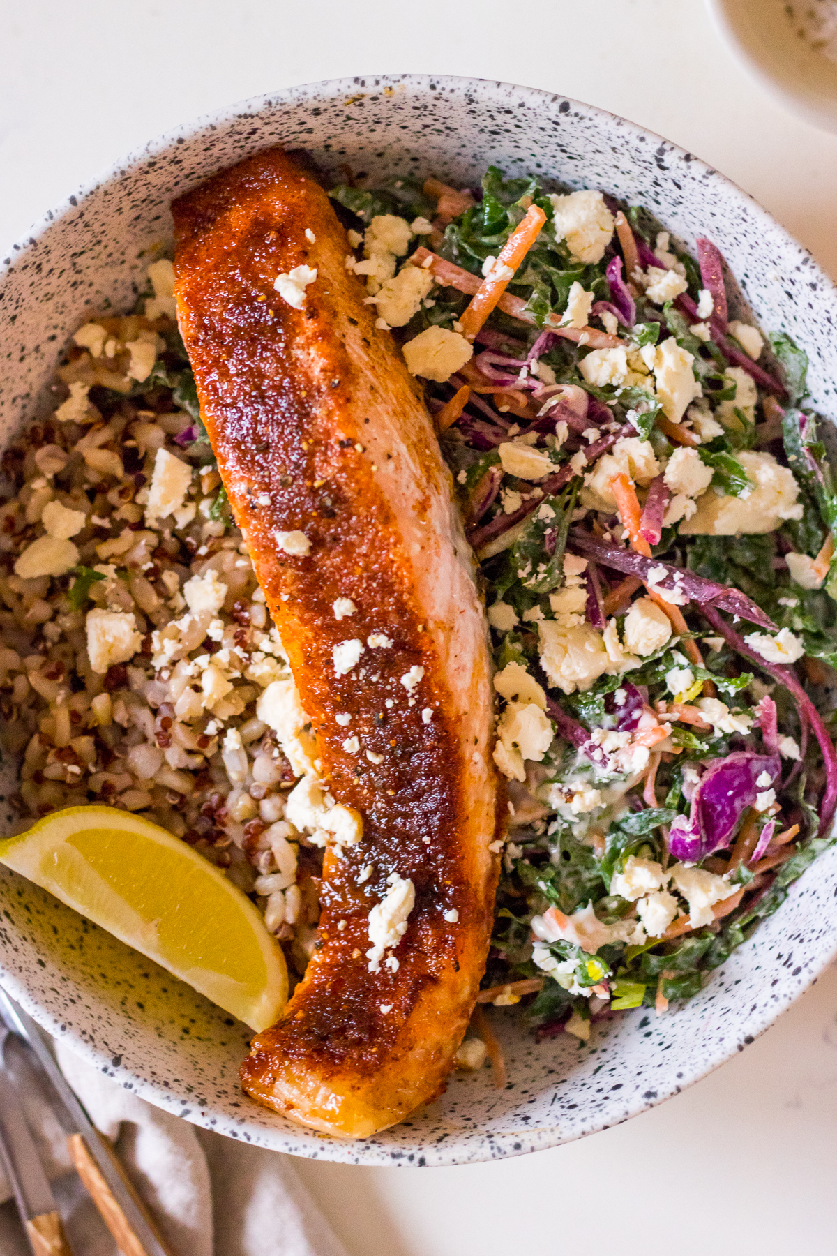 Speckled ceramic bowl filled with brown rice, coleslaw, salmon fillet baked with brown sugar