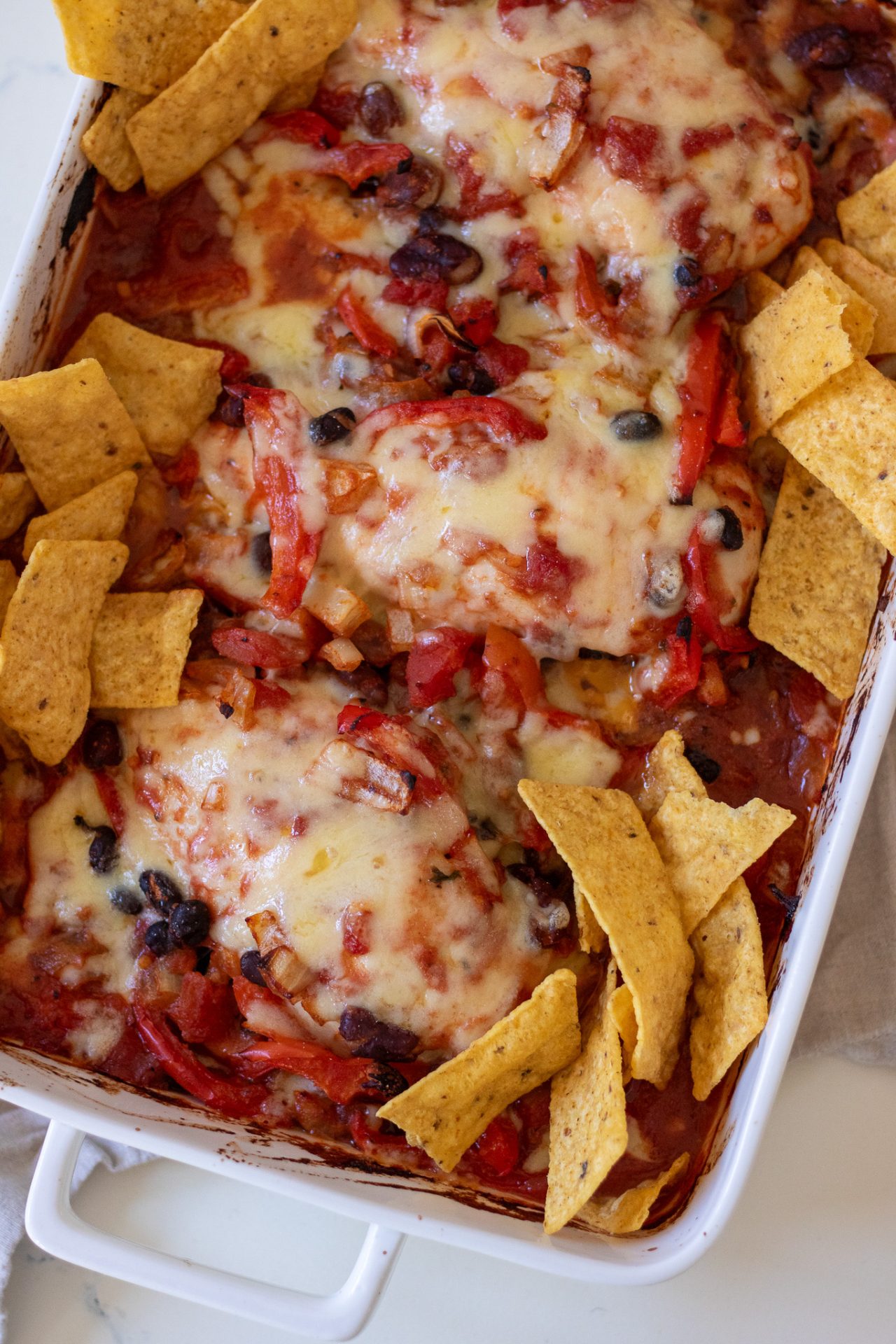 Healthy Chicken Taco Bake with bean mix, tomatoes, melted cheese and tortilla chips