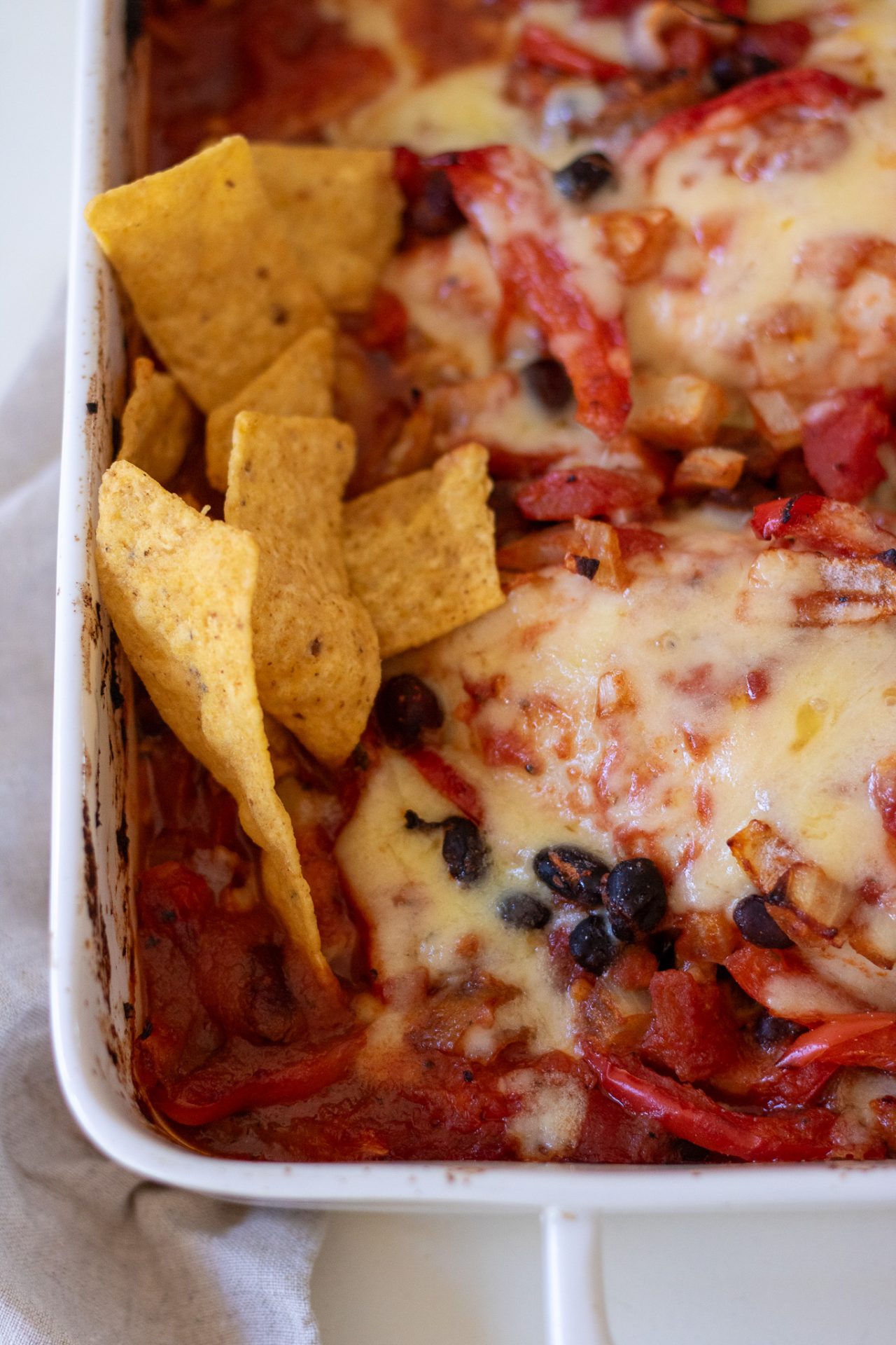 Taco Chicken Bake with Mexican flavours served with tortilla chips in a white baking dish