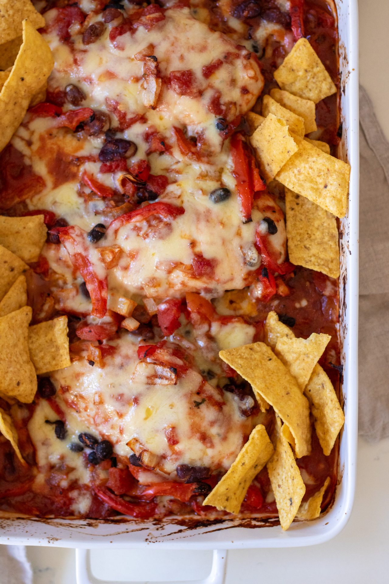 Healthy Chicken Taco Bake with black beans and tortilla chips in a white ceramic baking dish