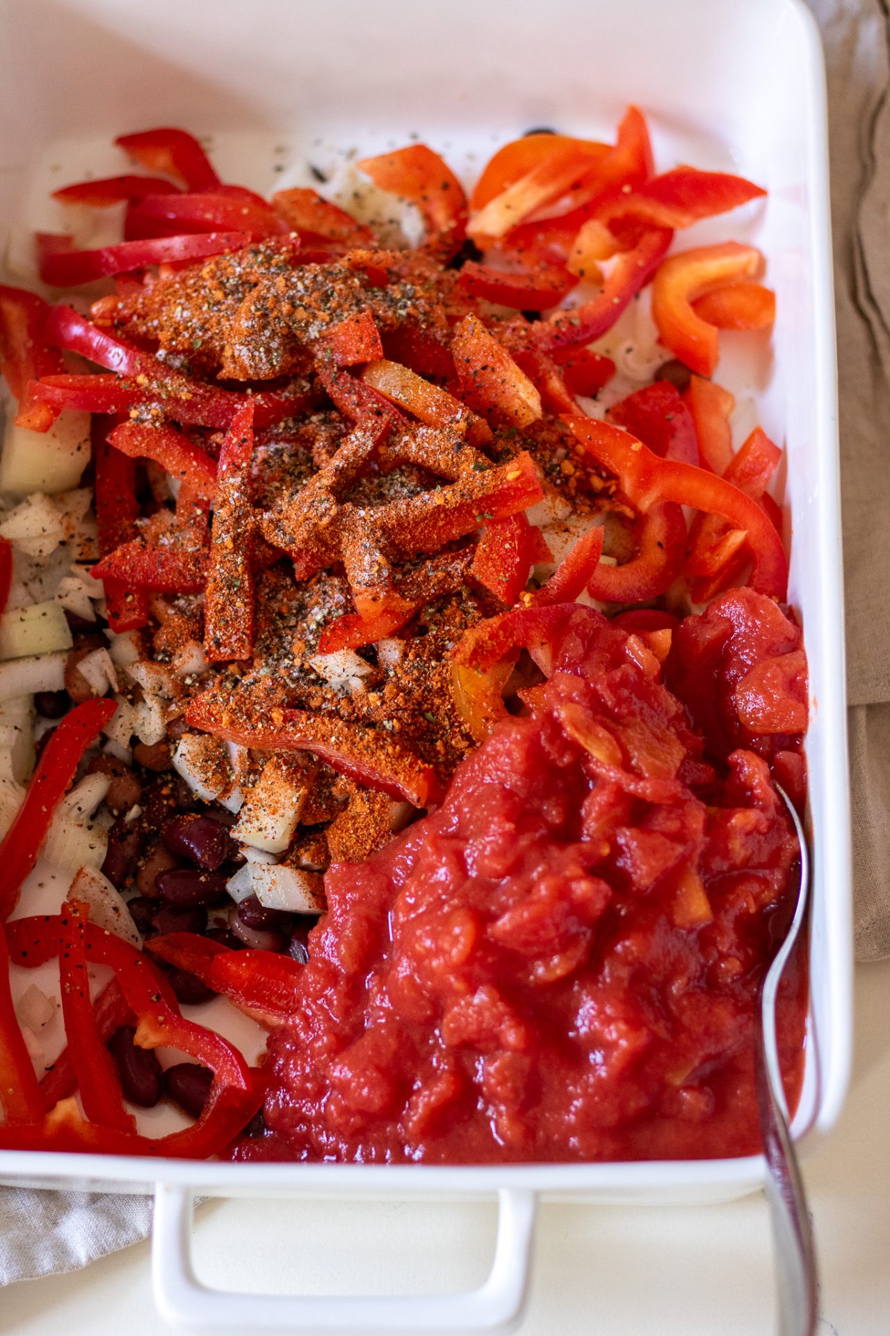 Image of ingredients for Mexican baked chicken; sliced capsicum, onion, taco seasoning, canned tomatoes, salt and pepper