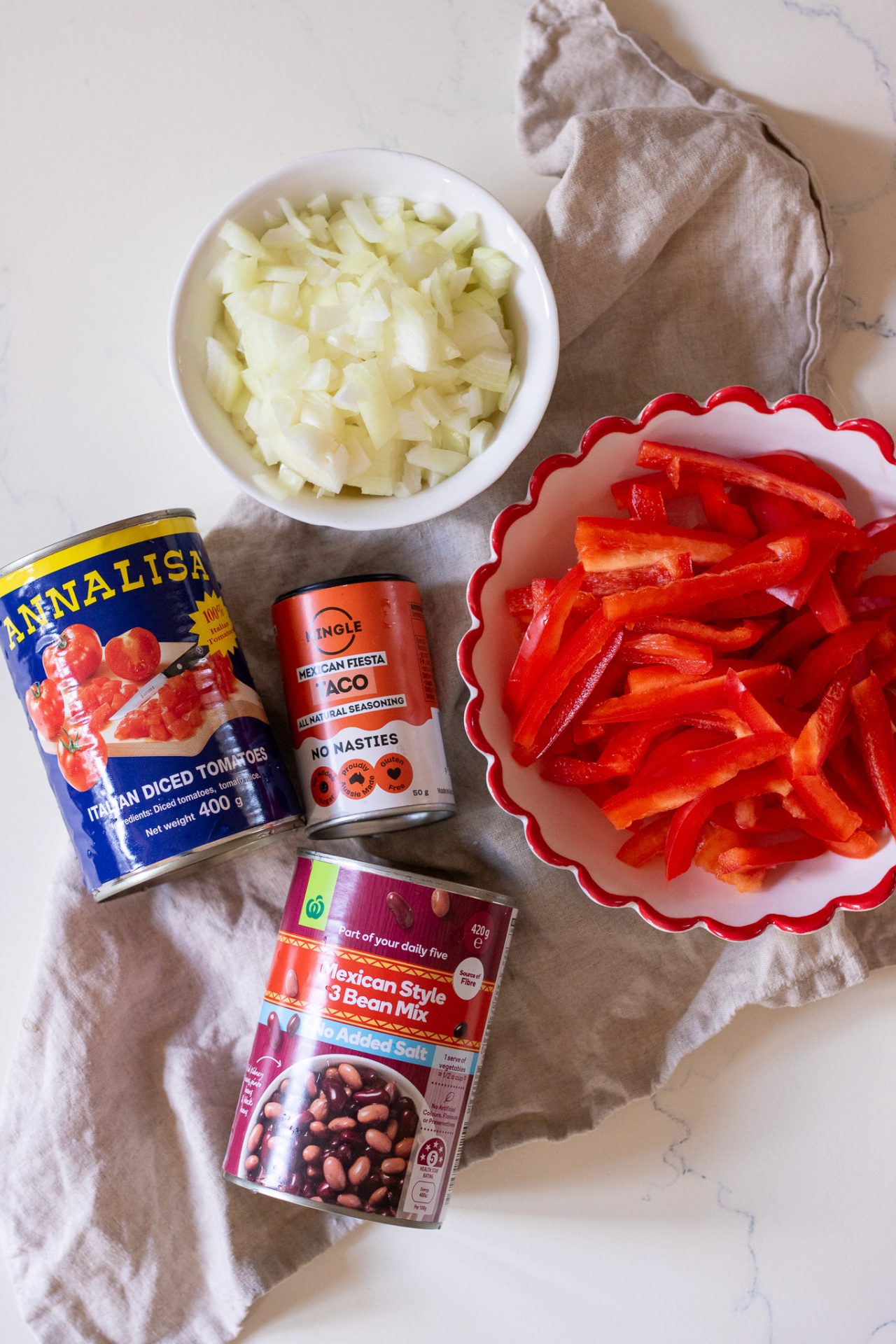 Ingredients needed for chicken taco bake; canned tomatoes, taco seasoning, canned bean mix, capsicum, onion