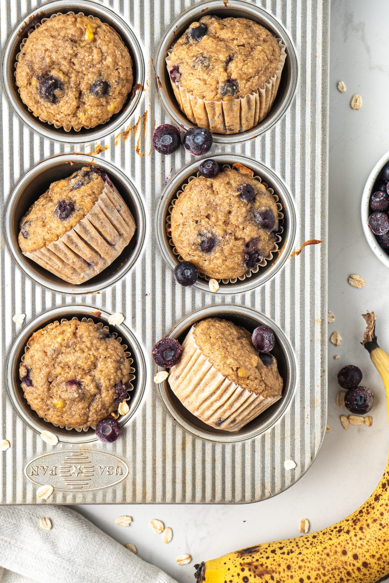 Healthy banana blueberry oat muffins arranged in a muffin baking tray.