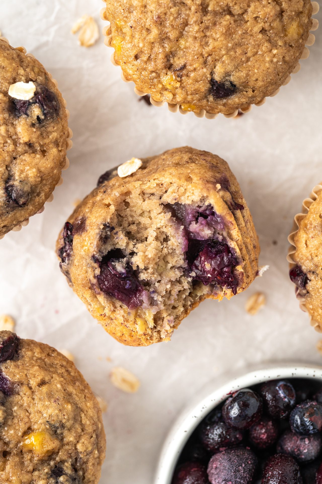 Banana blueberry oat muffin showing the fluffy inside with baked blueberries.