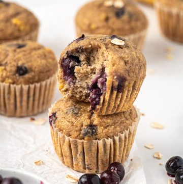 Banana blueberry oat muffins in a stack, showing the juicy baked blueberries inside.