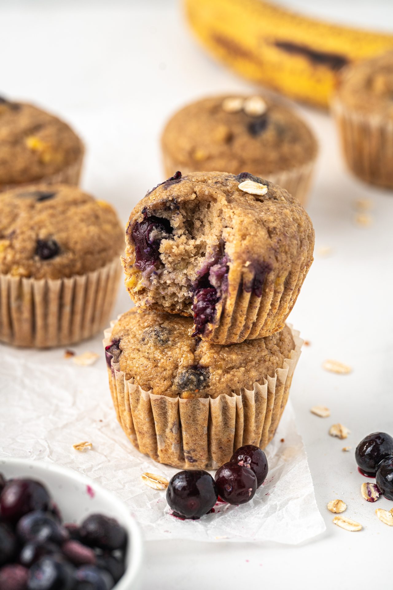 Banana blueberry oat muffins in a stack, showing the juicy baked blueberries inside.