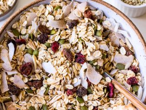 Large ceramic bowl filled with oat muesli with coconut flakes, pumpkin seeds and dried fruit