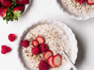 Bowl of oat and chia seed porridge topped with sliced strawberries