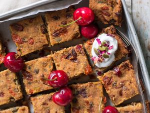 Nut Free Vegan Fruit Slice in baking tray topped with coconut yoghurt and fresh cherries!