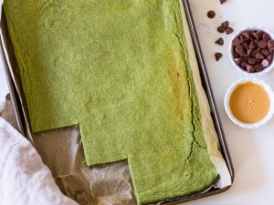 Image of healthy green pancakes baked in a baking tray, the edge cut into squares