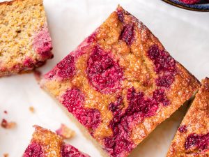 Orange cake topped with raspberries cut into square slices