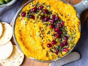 Roasted carrot tahini tip in a small grey dish on a wooden chopping board.