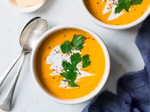 coconut ginger pumpkin soup bowl garnished with coconut cream and herbs