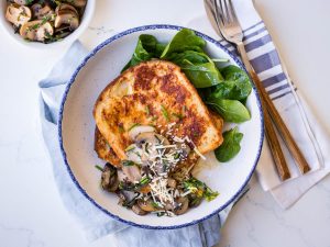 Savoury french toast with mushrooms and grated parmesan, white bowl