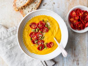 Cauliflower, sweet potato and red lentil soup in white patterned bowl with bread