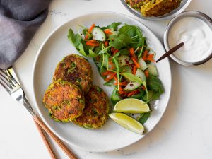 thai salmon cakes on white plate with side salad and lime